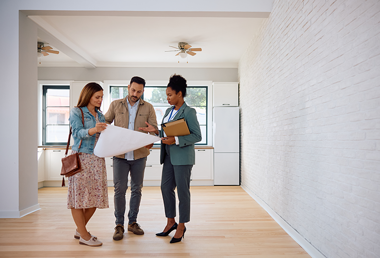Couple looks at rental home blueprints with realtor