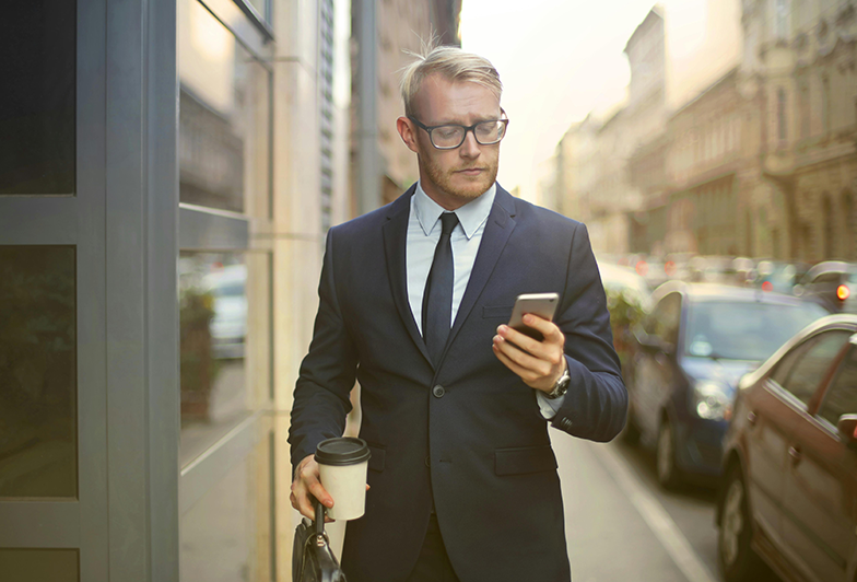 Man checks his investments on his phone in city street